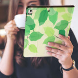 a girl is holding and viewing personalized iPad folio case with Leaves design